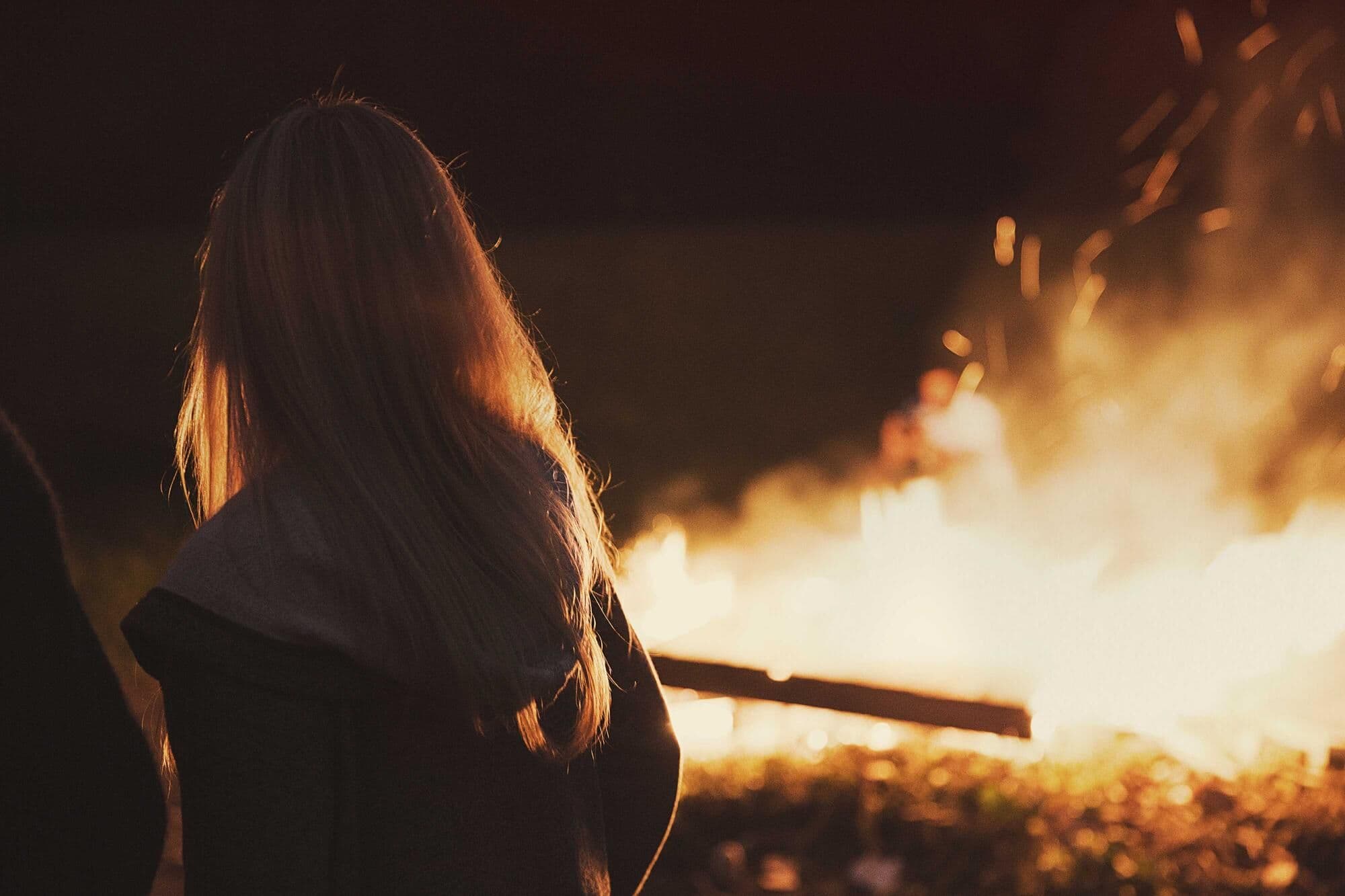 Someone silhouetted against a big campfire at night