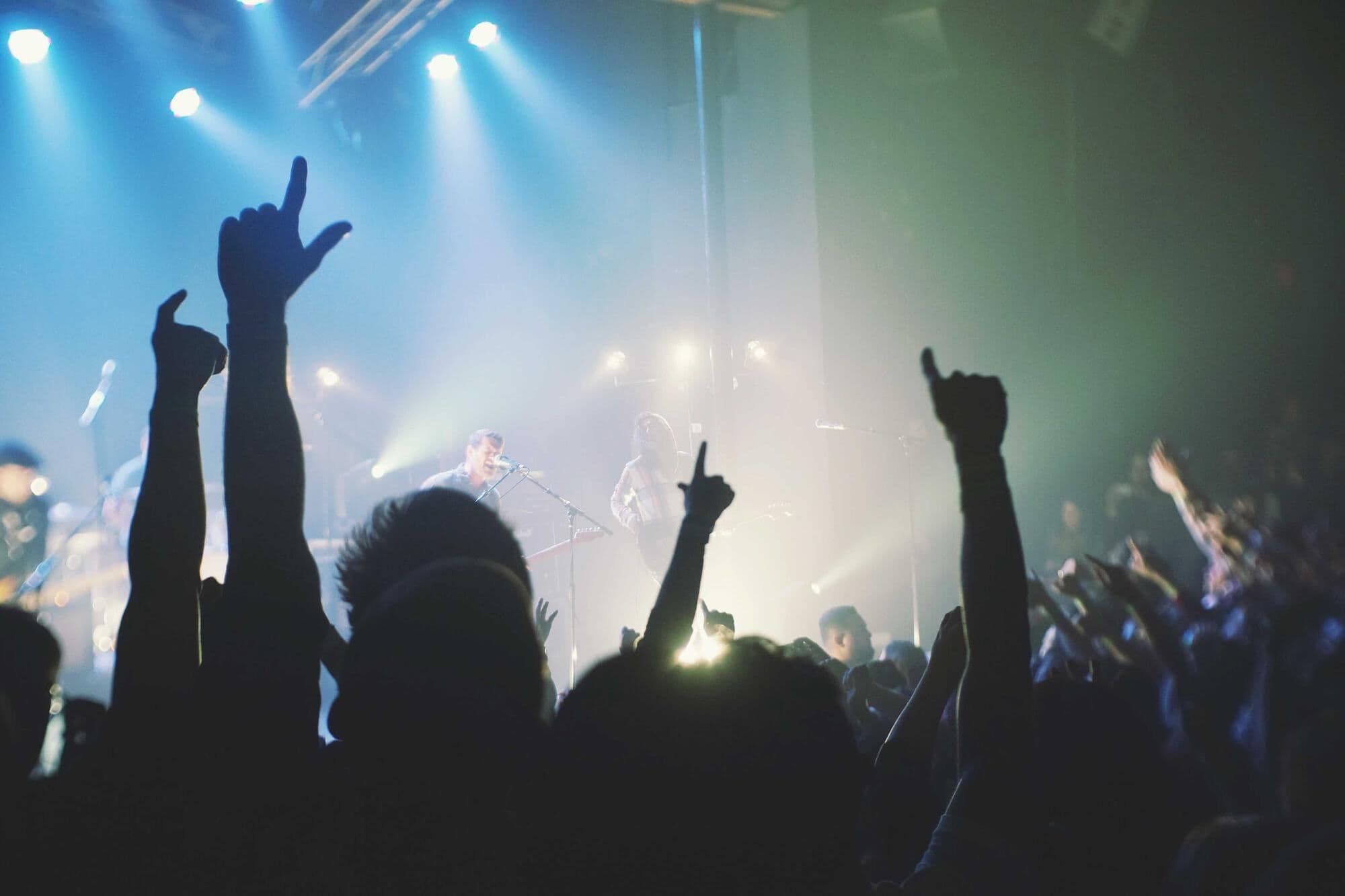 A crowd with hands in the air under stage lights