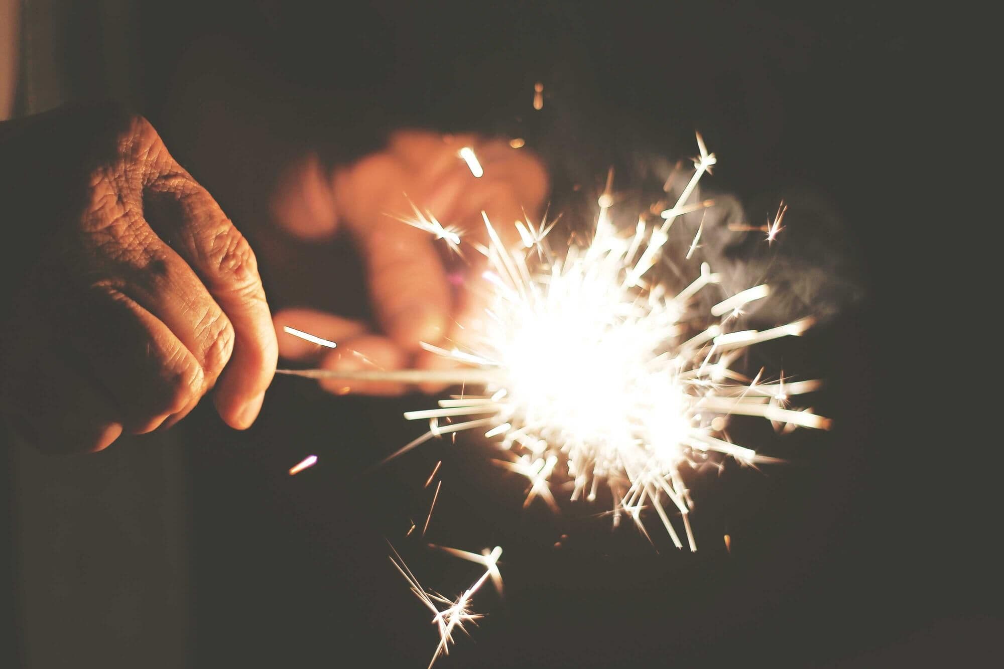Hands lighting a sparkler in the dark